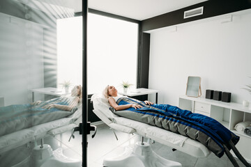 Relaxed woman enjoying in pressotherapy treatment at wellness center or clinic. wide angle - 548291370