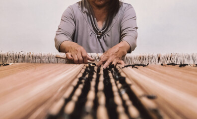 Argentinian artisan weaving a traditional brown poncho on the loom - South American typical crafts - Selective focus