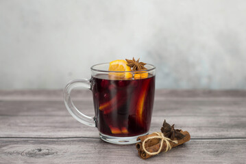 Mulled wine with orange in a glass on grey and brown background.