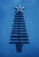 Handmade craft Christmas tree made from wooden planks and illuminated garland as outdoor wall decoration. Xmas upcycling handicraft design, toned image