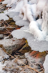 Winter landscape with snow-covered rocks and grass on the river bank