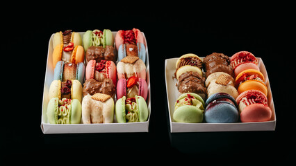 Gift set of large colored macaroons with different fillings and decorations, on a black isolated background. Confectionery concept.