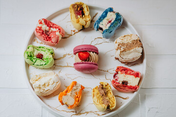 Many big bitten macaroons on a beautiful white plate, on a white background. Photo for content.