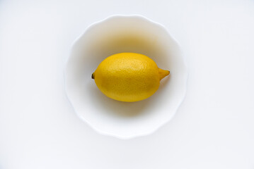 Yellow juicy lemons in a white saucer. Delicious yellow lemons on a white background. Beautiful lemons on a plate.