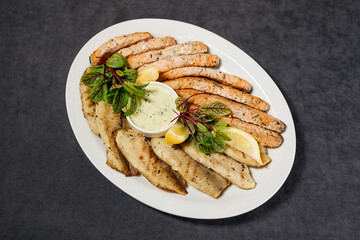 Assorted grilled fish with sauce. Decorated with lemon and herbs. Restaurant concept.