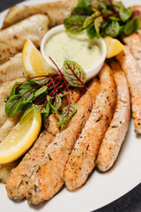 Assorted grilled fish with sauce. Decorated with lemon and herbs. Restaurant concept.
