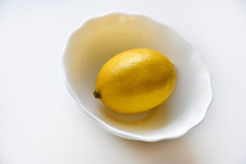 Yellow juicy lemons in a white saucer. Delicious yellow lemons on a white background. Beautiful lemons on a plate.