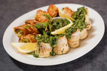 Assorted grilled fish with sauce. Decorated with lemon and herbs. Restaurant concept.