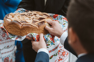 Groom plucking on an ukrainian wedding bread - 548296956