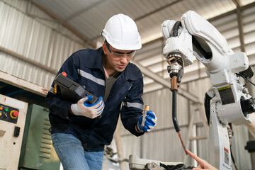 Robotics engineer working on maintenance of modern robotic arm in factory warehouse