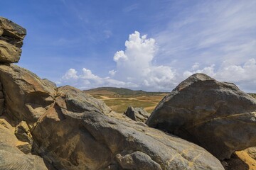 Beautiful nature landscape view. Big rocks on front and desert and mountains on blue sky with white clouds background. Aruba.