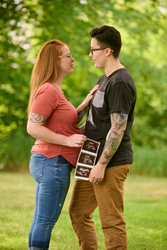 Same sex female couple holding ultrasound of unborn baby.