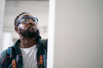 A furniture workshop making bespoke contemporary furniture pieces using traditional skills in modern design. A man in ear defenders holding wood, using a machine.