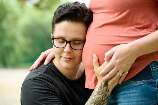Female hugging pregnant partners stomach.