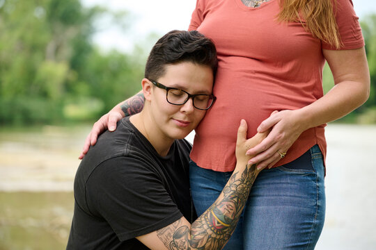 Female hugging pregnant partners stomach.