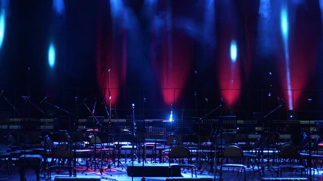Concert light. Stage lighting background. An empty stage and a hall without people. There are a lot of empty chairs and microphones on the stage for musicians.