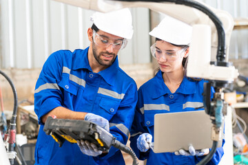 Robotics engineer working on maintenance of modern robotic arm in factory warehouse