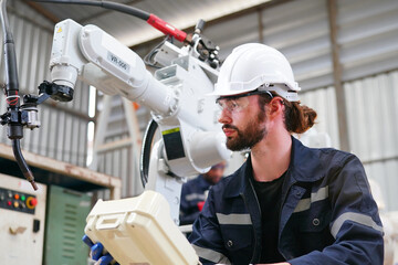 Robotics engineer working on maintenance of modern robotic arm in factory warehouse