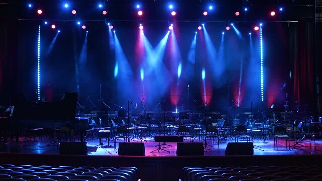 Concert light. Stage lighting background. An empty stage and a hall without people. There are a lot of empty chairs and microphones on the stage for musicians.