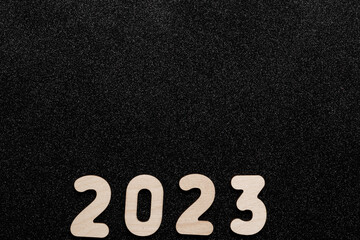 New Year's card 2023. Wooden numbers of the year on a black shiny starry background. New Year greeting card template. Festive layout.