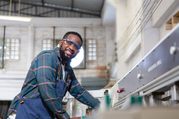 A furniture workshop making bespoke contemporary furniture pieces using traditional skills in modern design. A man in ear defenders holding wood, using a machine.