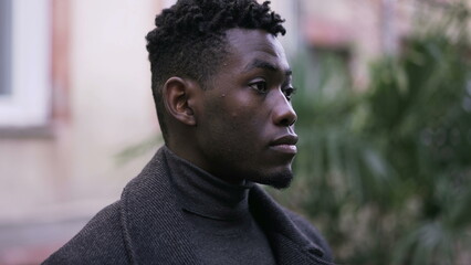 Serious young black man standing outdoors. Stoic handsome African person