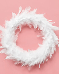 White feathers wreath on yellow background with copy space top view. Easter decoration