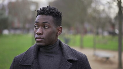 Fototapeta premium Satisfied young black African man walking outside at park nature feeling happy