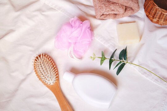 Organic shampoo, natural soap, wooden hair brush, pink sponge, towel and eucalyptus branch on a white background. Flat lay beauty photo. Herbal cosmetics top view image