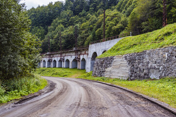 Fototapeta na wymiar Road in Carpathians view. Old railway bridge in the mountains. Ukrainian Carpathians