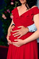 Guy and pregnant girl hold hands on their belly