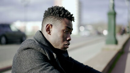 Preoccupied young black man. Anxious person sitting on the ground in city sidewalk