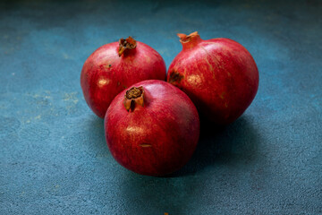 Fototapeta na wymiar Three pomegranates lie on a blue background