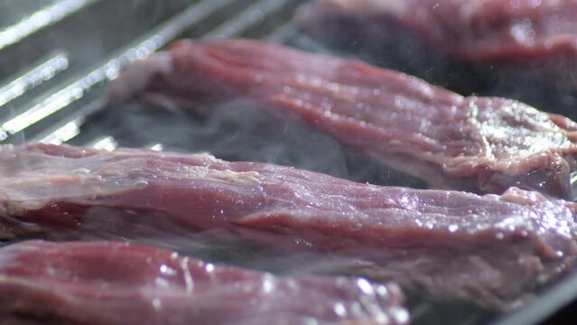 Raw beef steaks cooking at grill
