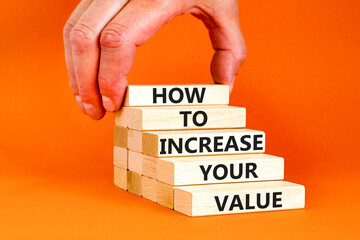 Increase your value symbol. Concept words How to increase your value on wooden blocks. Businessman hand. Beautiful orange background. Business how to increase your value concept. Copy space.