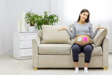 Photo of positive pregnant woman with pink and blue papers on the stomach which mean gender of future baby.