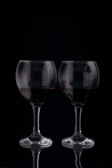 glasses of red wine on a black background with reflection