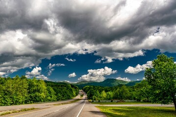 Rural asphalt freeway in South Carolina surrounded by scenic greenery under the cloudy sky