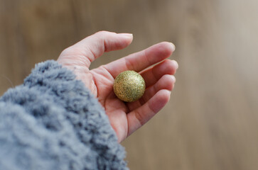 Mano humana sujetando una bola de navidad de purpurina dorada