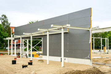 Unfinished steel construction frame of a new modern warehouse with gray sandwich panel wall
