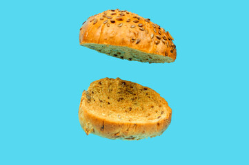 A two-piece rye burger bun in a state of levitation on a blue background.