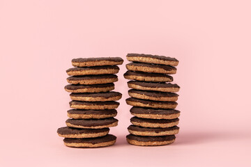 Stacks of chocolate-covered cookies on pink background