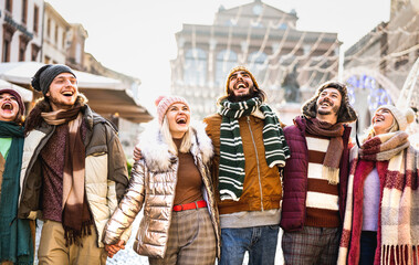 Happy students group walking at european city on sunny winter day - Next gen z life style concept with multiracial young people wearing warm clothes having fun together outdoors - Backlight filter - obrazy, fototapety, plakaty