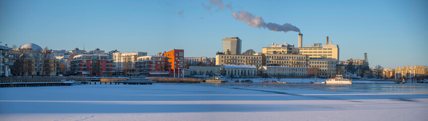 Panorama, snowy winter view at the bay Hammarby Sjö, low solstice, long shadows and clear sky, in...