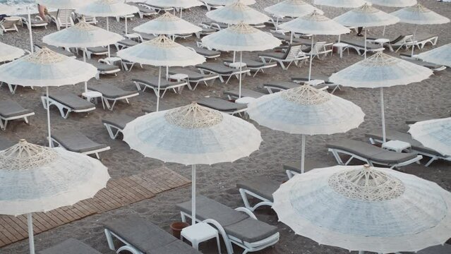 Empty Beach, Rows of folded beach umbrellas and empty sunbeds in Turkey, early morning. Italy or Greece. Top view. Travel and leisure concepts.