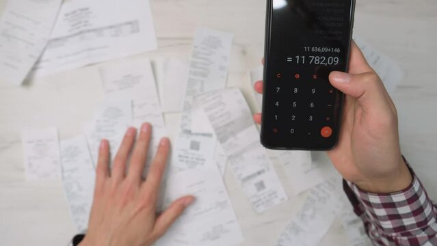 A man counts money in cash dollars, euros. Summary and analysis of expenses and income for goods and services and salary. A person calculates utility bills and receipts using a smartphone calculator.