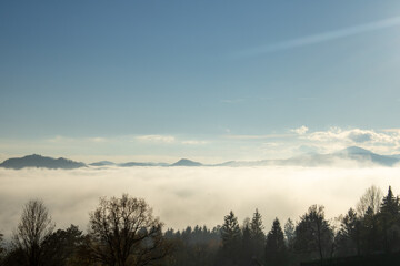 Fototapeta na wymiar Heavy fog and mist surrounds forested mountain peaks