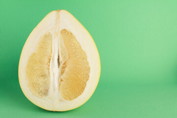 Close up fresh juicy ripe cut sliced yellow Pomelo on green color background. Shaddock, citrus...