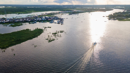 Small boat navigating the Amazon River at sunset towards Iquitos, Peru, South America.