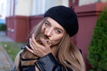 Fototapeta premium A young, beautiful girl with a kitten and bread on the streets of the city.